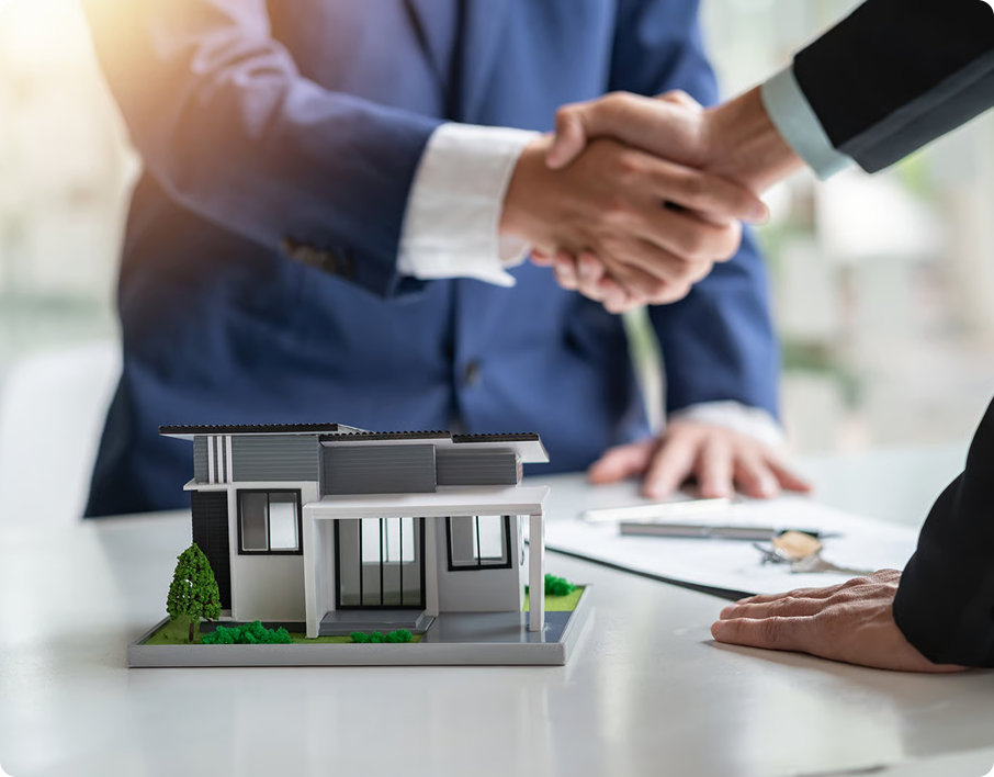 Real estate advisors shaking hands over a model home